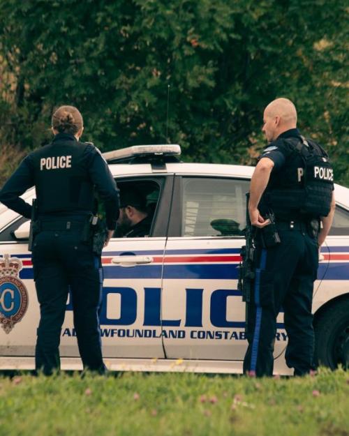 		Two police officers stand near a police car
	