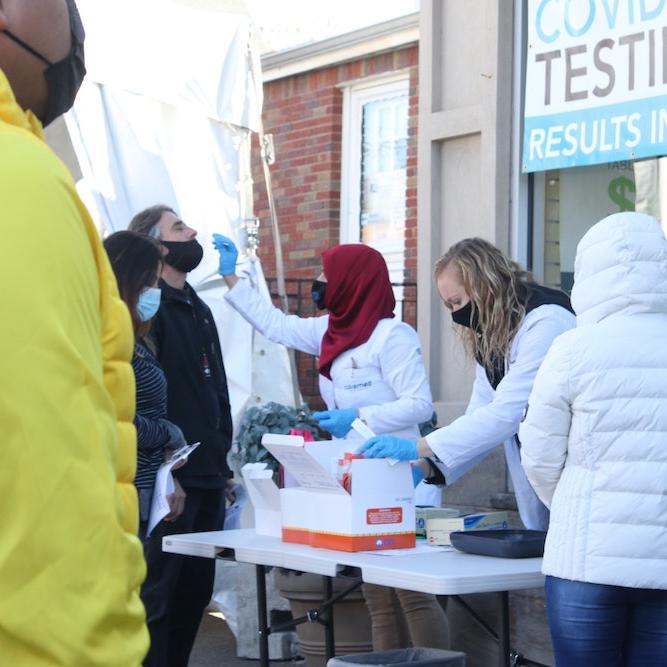 		People administer COVID tests at an outdoor table
	