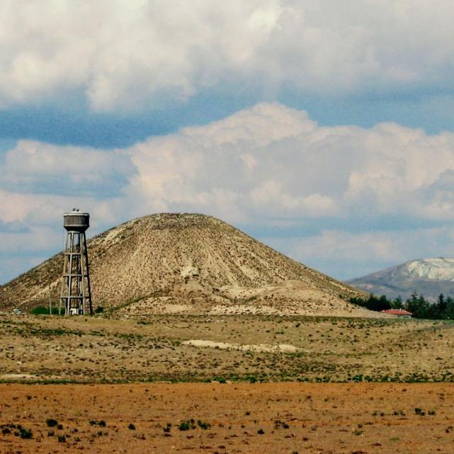		Dry landscape featuring a hill and partly cloudy sky
	