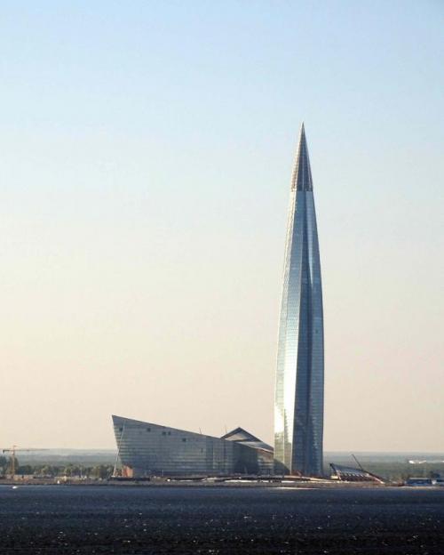 		A rocketship-shaped skyscraper next to a building shaped like the prow of a ship, both steel-colored.
	