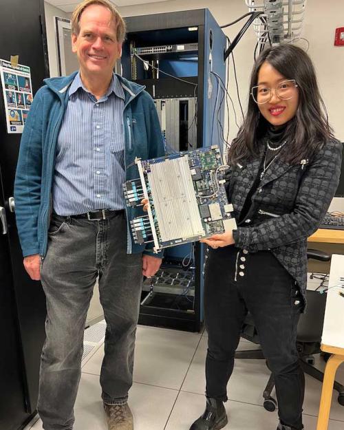 		Two people hold a laptop-sized piece of equipment
	