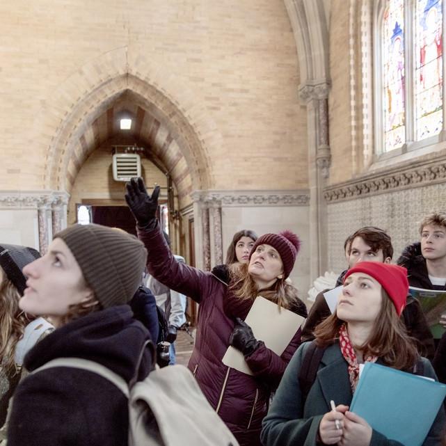 Group of people in winter clothing look up in an old building