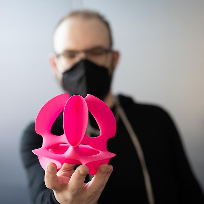 Person wearing black holds out an elaborate pink shape