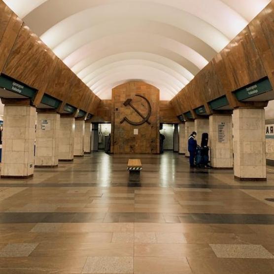 Interior of a building with arched ceiling and smooth floors; Soviet symbol carved into far wall