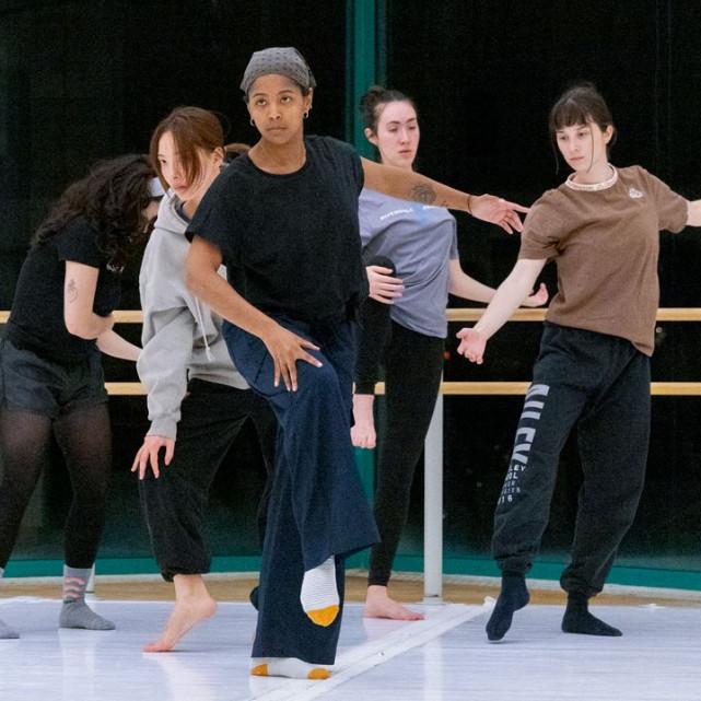 Five people perform a dance, creating a V formation with their bodies