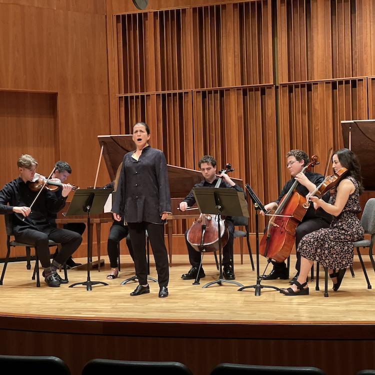 Six musicians--a singer, four string players and a pianist--perform on stage