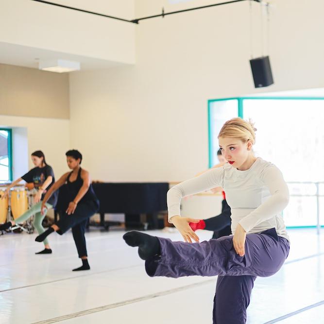 		Several people dancing in formation in a sunny studio
	
