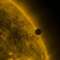  Small black sphere in front of a fiery large sphere