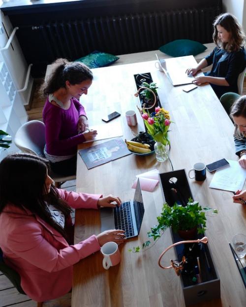 Five people working on laptops at a long table