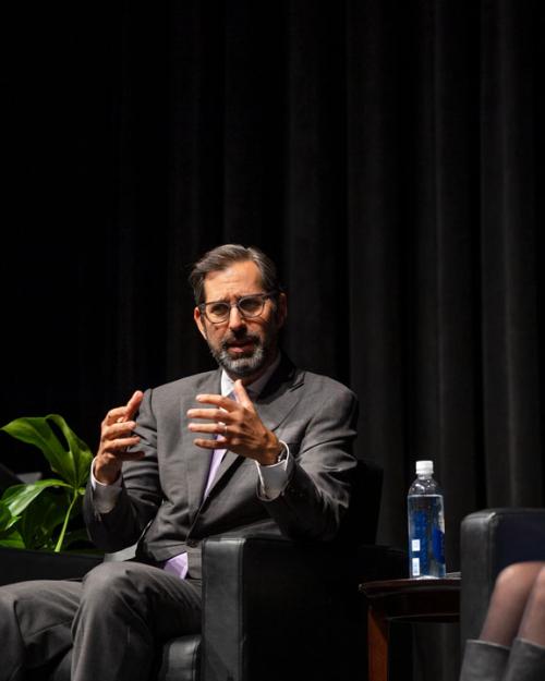 Three people sitting in chairs on a stage