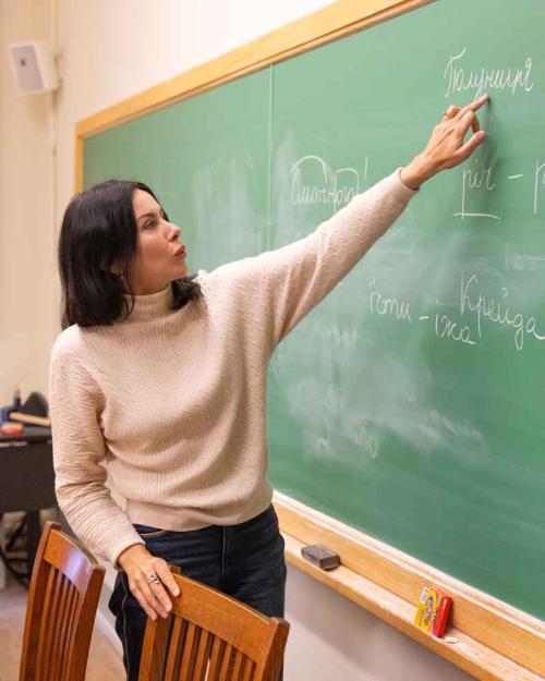 		woman showing Ukrainian words on chalkboard
	