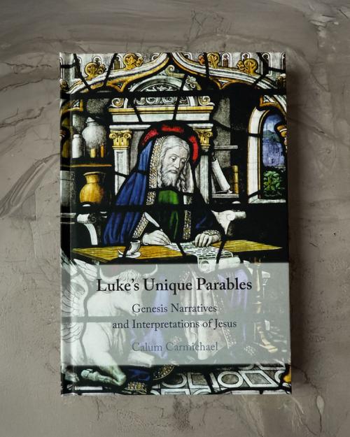 Image of aMedieval scholar sitting at a table writing with a quill pen